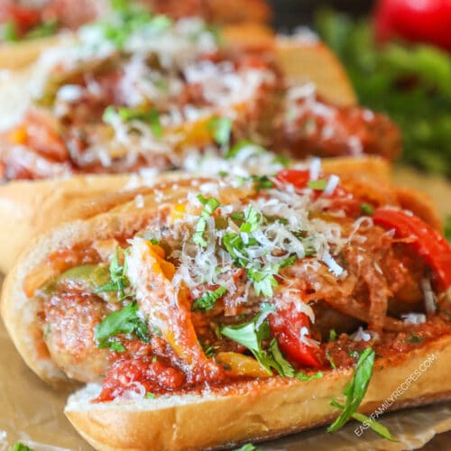 Side view of sausage and peppers served in a roll, topped with parmesan and parsley.