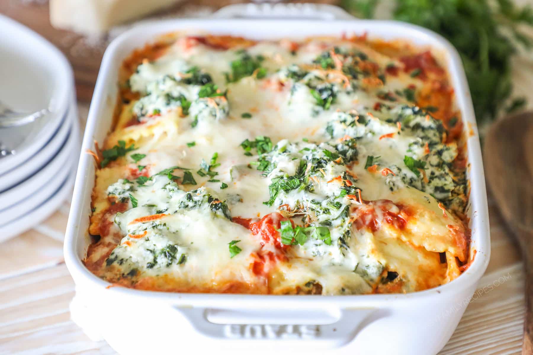 Side view of ravioli lasagna in a white baking dish.