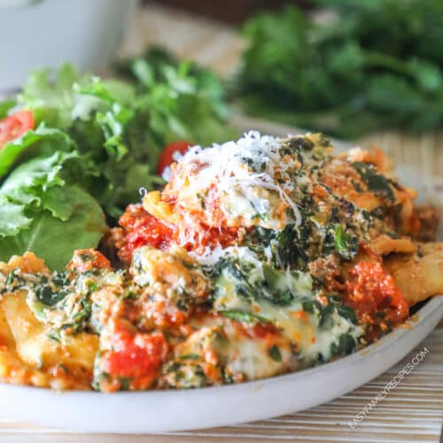 Portion of ravioli lasagna served on a plate with a side salad.