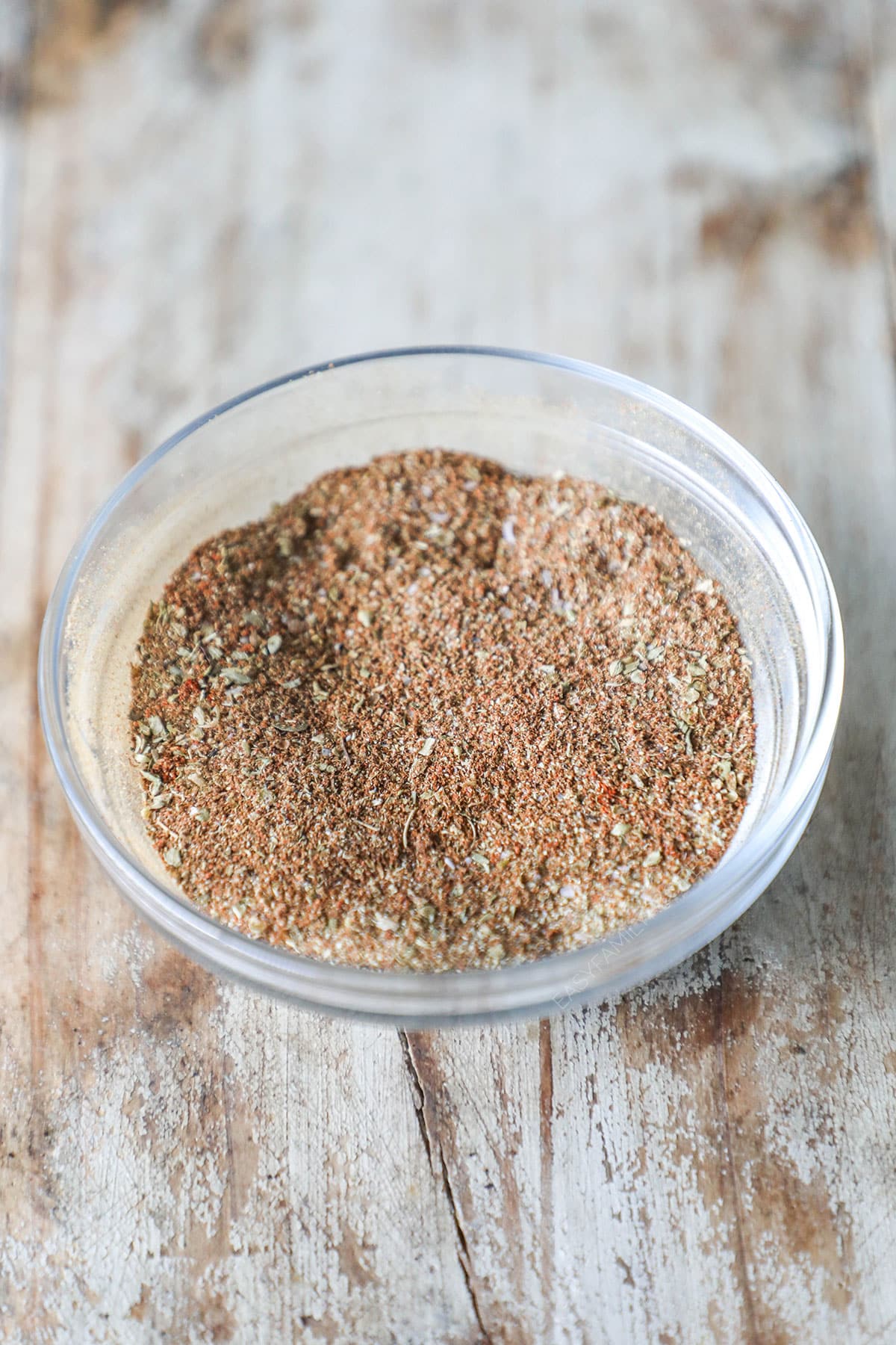 Carne Asada Seasoning Blend mix together in a clear bowl. On a wooden background