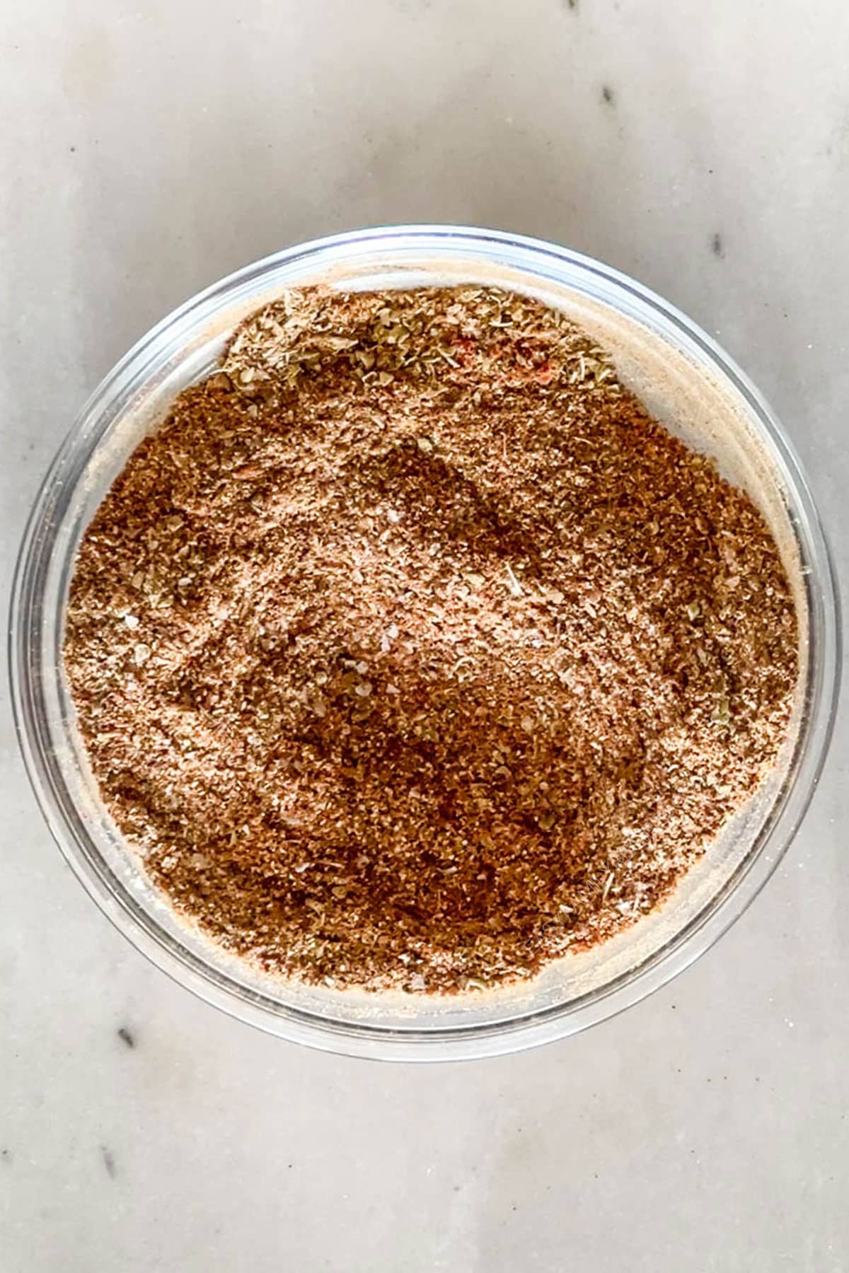 Carne Asada Seasoning Blend mix together in a clear bowl. On a wooden background