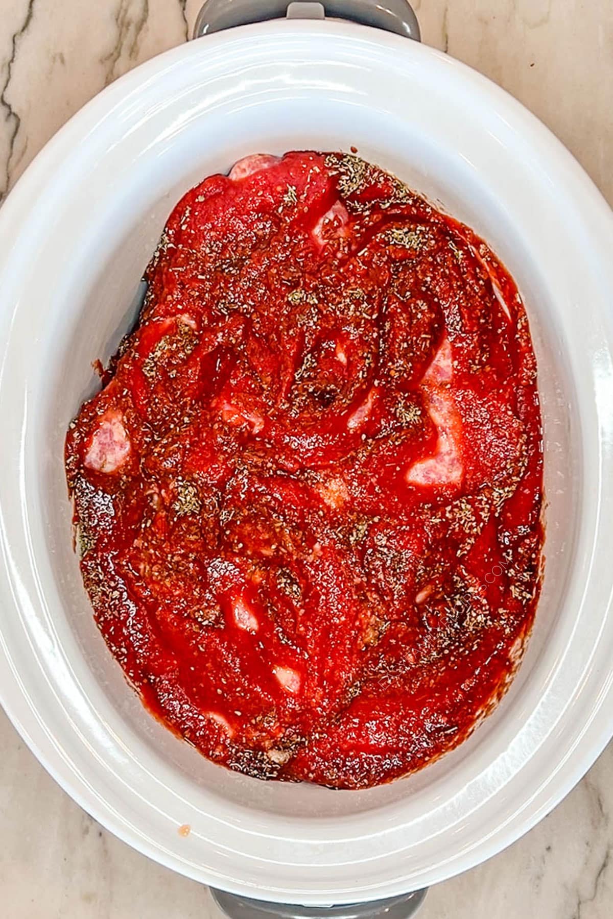 Crushed tomatoes poured over the sausages and peppers in a crockpot.