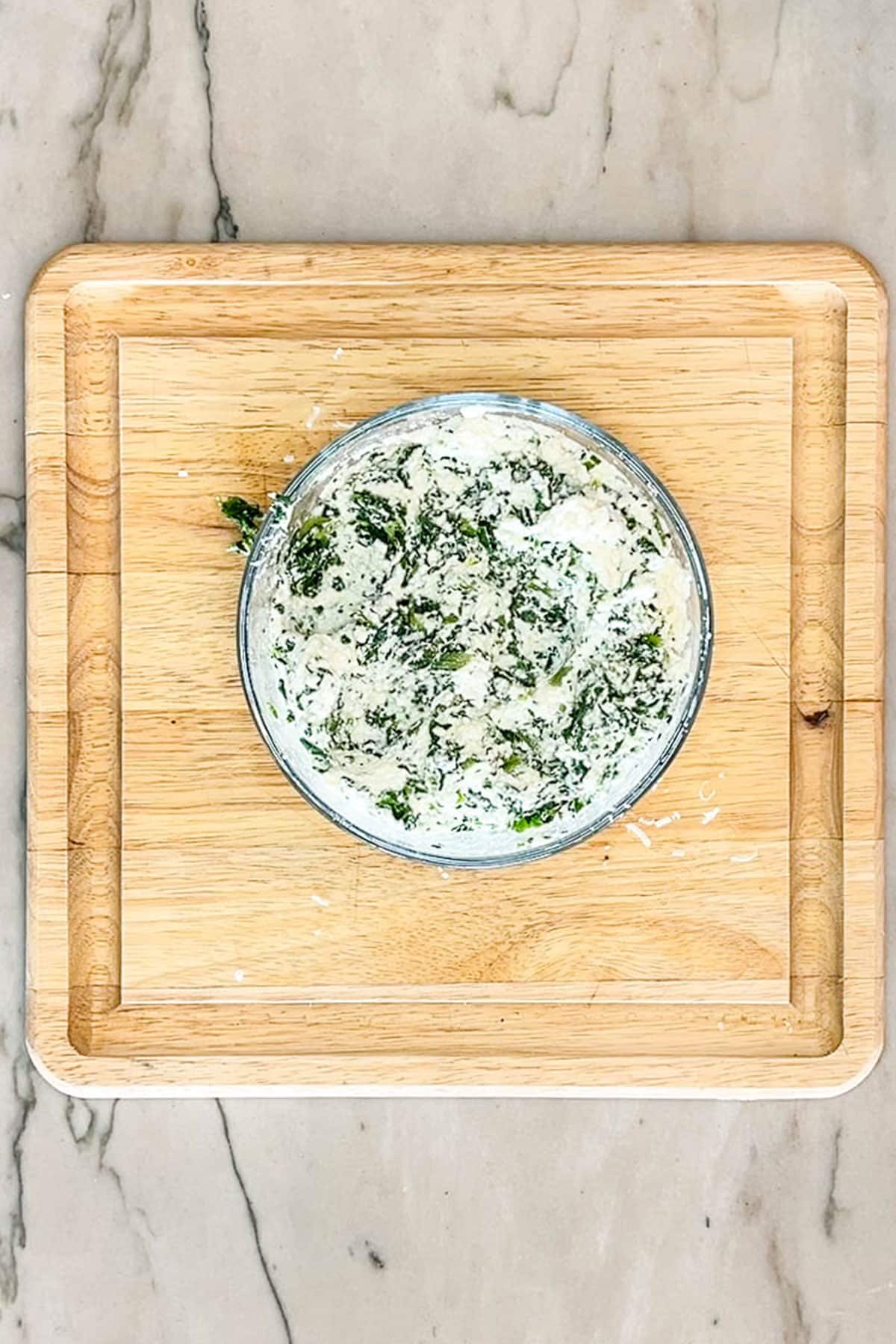 Ricotta and spinach mixed together in a glass container.