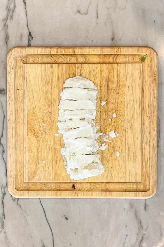 sliced goat cheese on a cutting board.