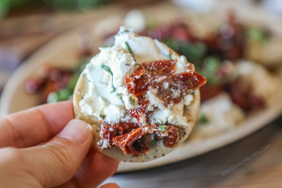 a cracker spread with marinated goat cheese and held.