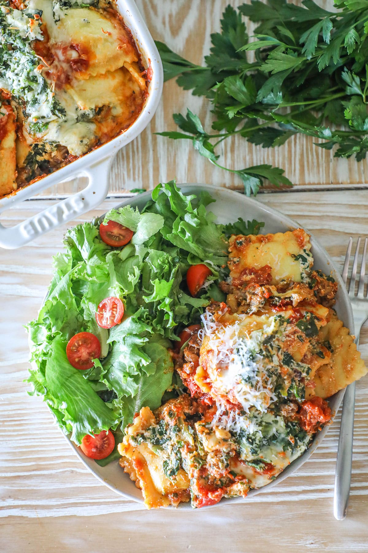 Overhead shot of ravioli lasagna on a plate with a side of salad.