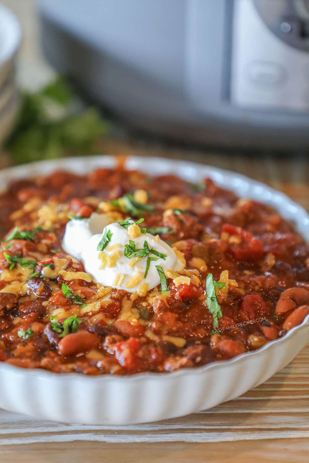 Side view of a shallow bowl of crockpot taco chili, garnished with sour cream and cilantro.