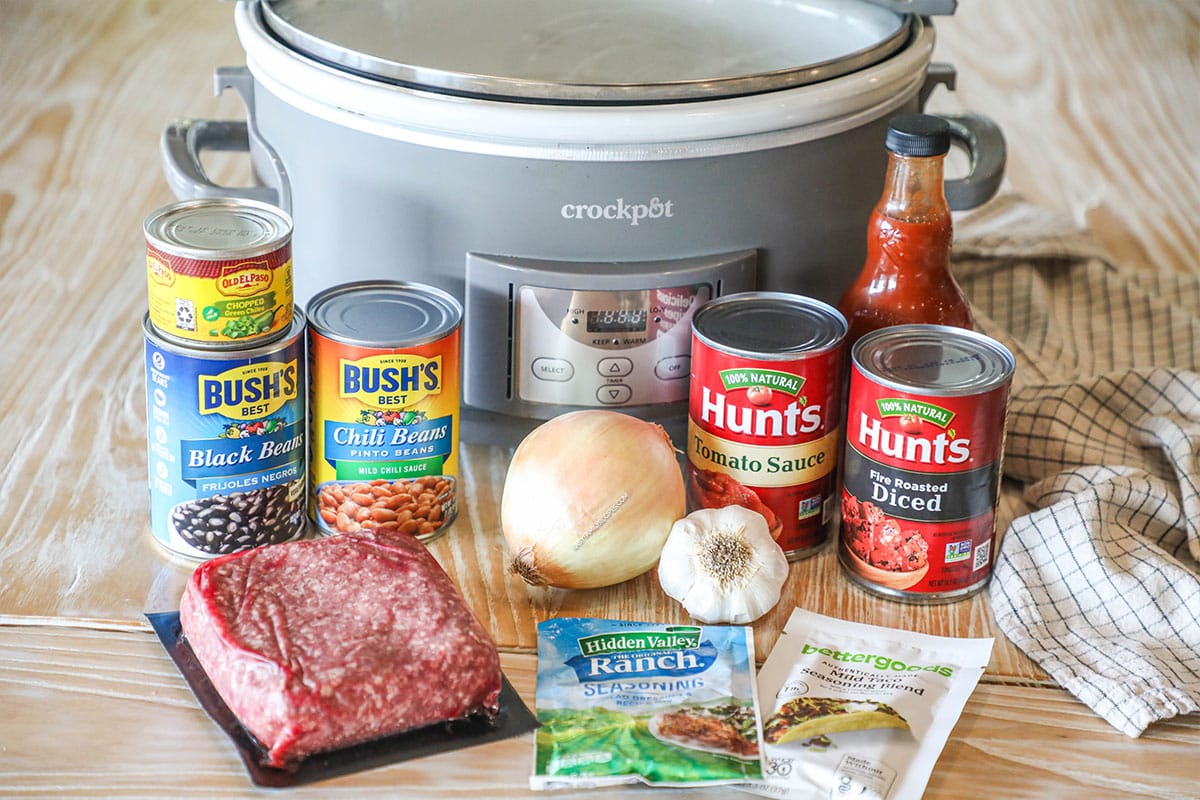 Ingredients needed to make crockpot taco chili on a wooden background.