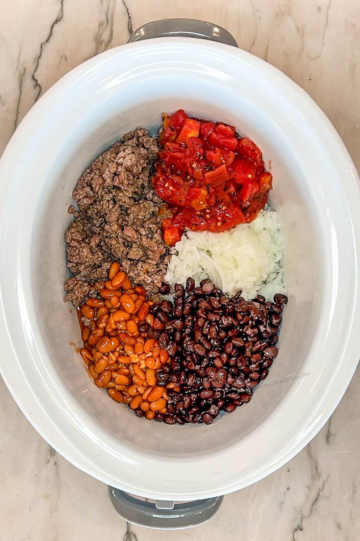 Beef, beans, onion, and peppers in a crockpot.