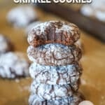 Brownie Crinkle Cookies stacked- top cookies show fudgy inside- on a parchment paper background