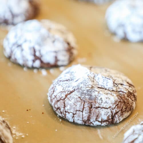 Close up of baked Brownie Crinkle Cookies- on a parchment paper lined sheet pan