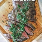 Chimichurri Flank Steak grilled, sliced and topped with fresh chimichurri sauce. On a wooden cutting board