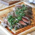Chimichurri Flank Steak grilled, sliced and topped with fresh chimichurri sauce. On a wooden cutting board
