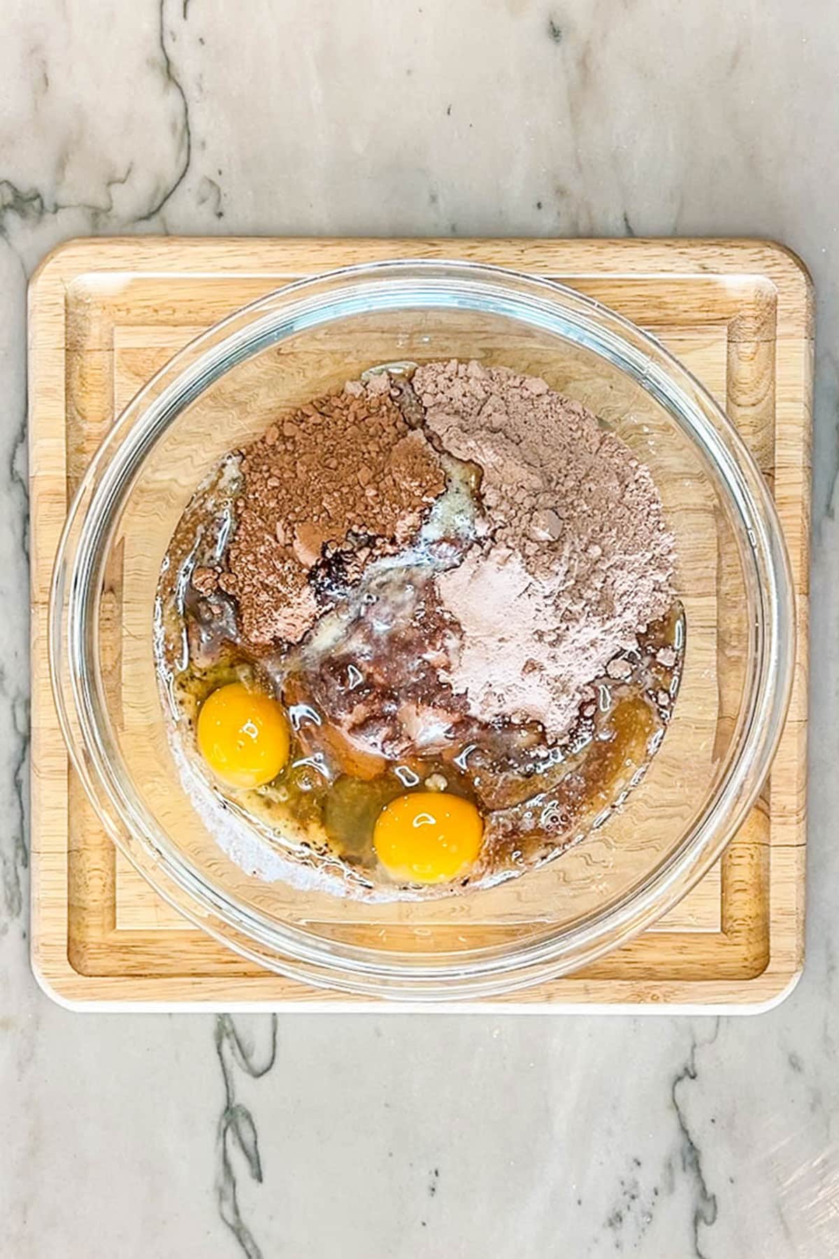 Step 1 for making Brownie Crinkle Cookies- Ingredients combined in glass bowl on wooden board
