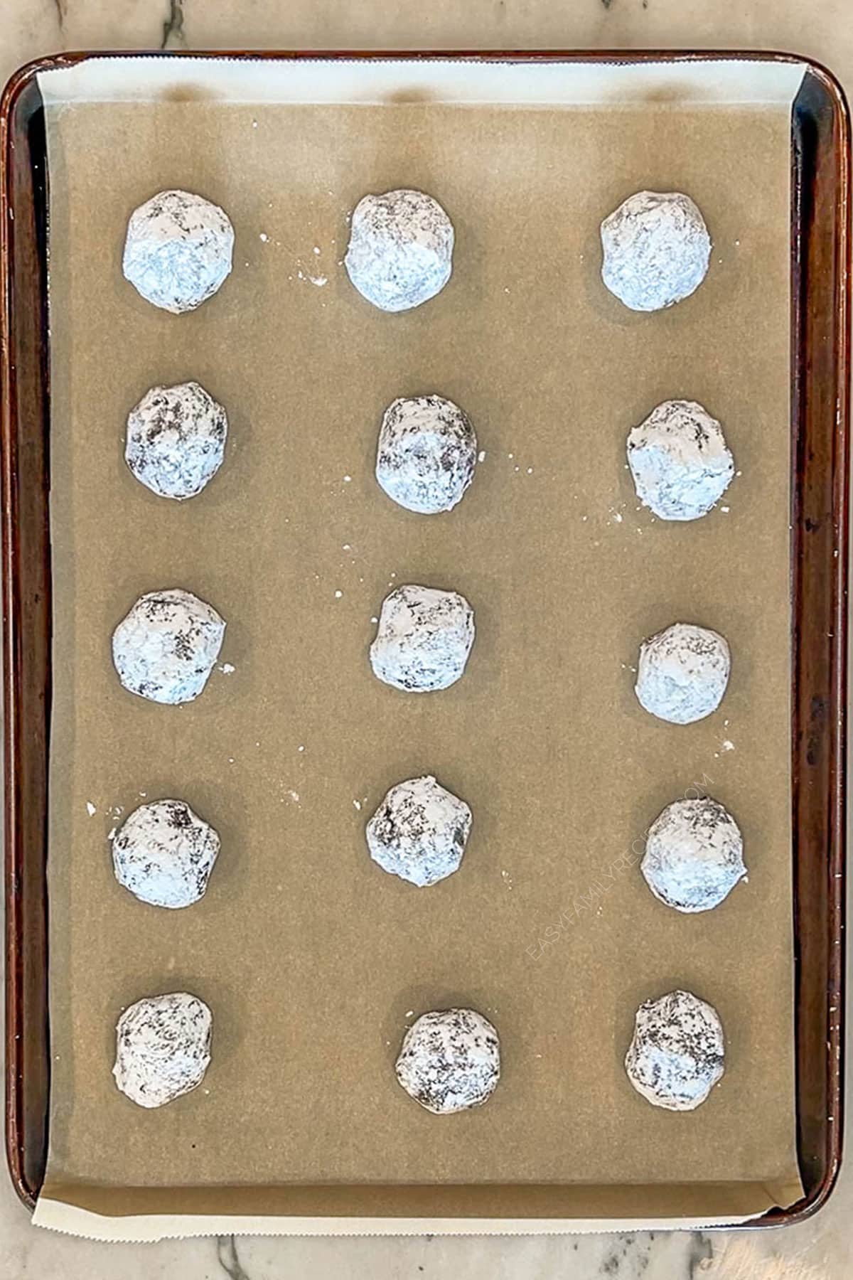 Step 4 for making Brownie Crinkle Cookies- place dough balls on parchment lined cookie sheet