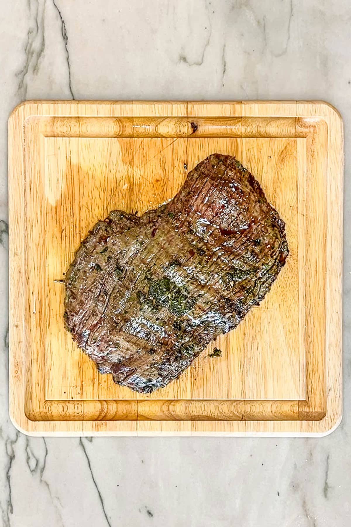 Grilled chimichurri flank steak on a wooden cutting board