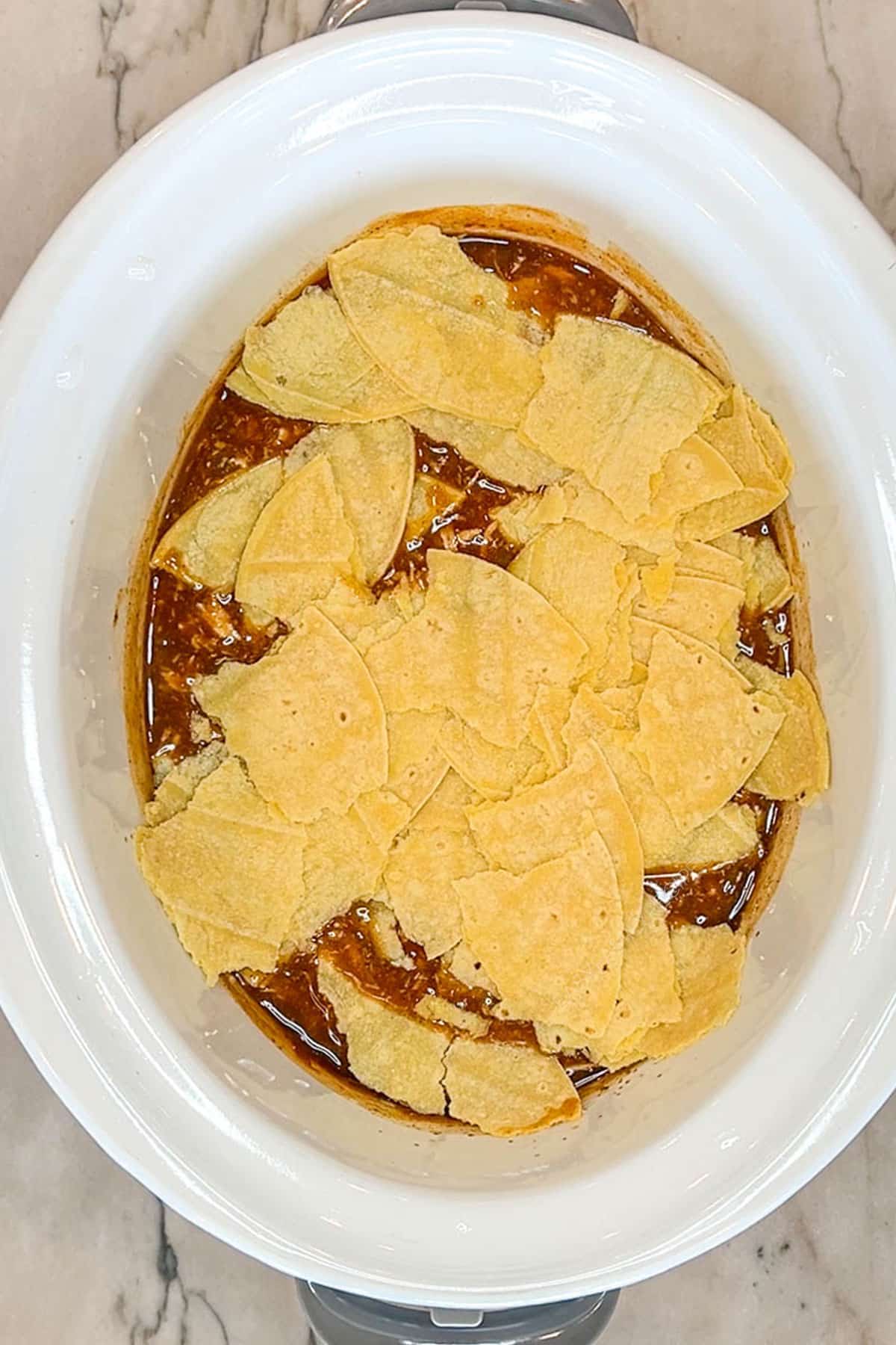 Crockpot Enchilada Chicken Casserole- step 4. put torn tortillas into crock pot. In a white crockpot