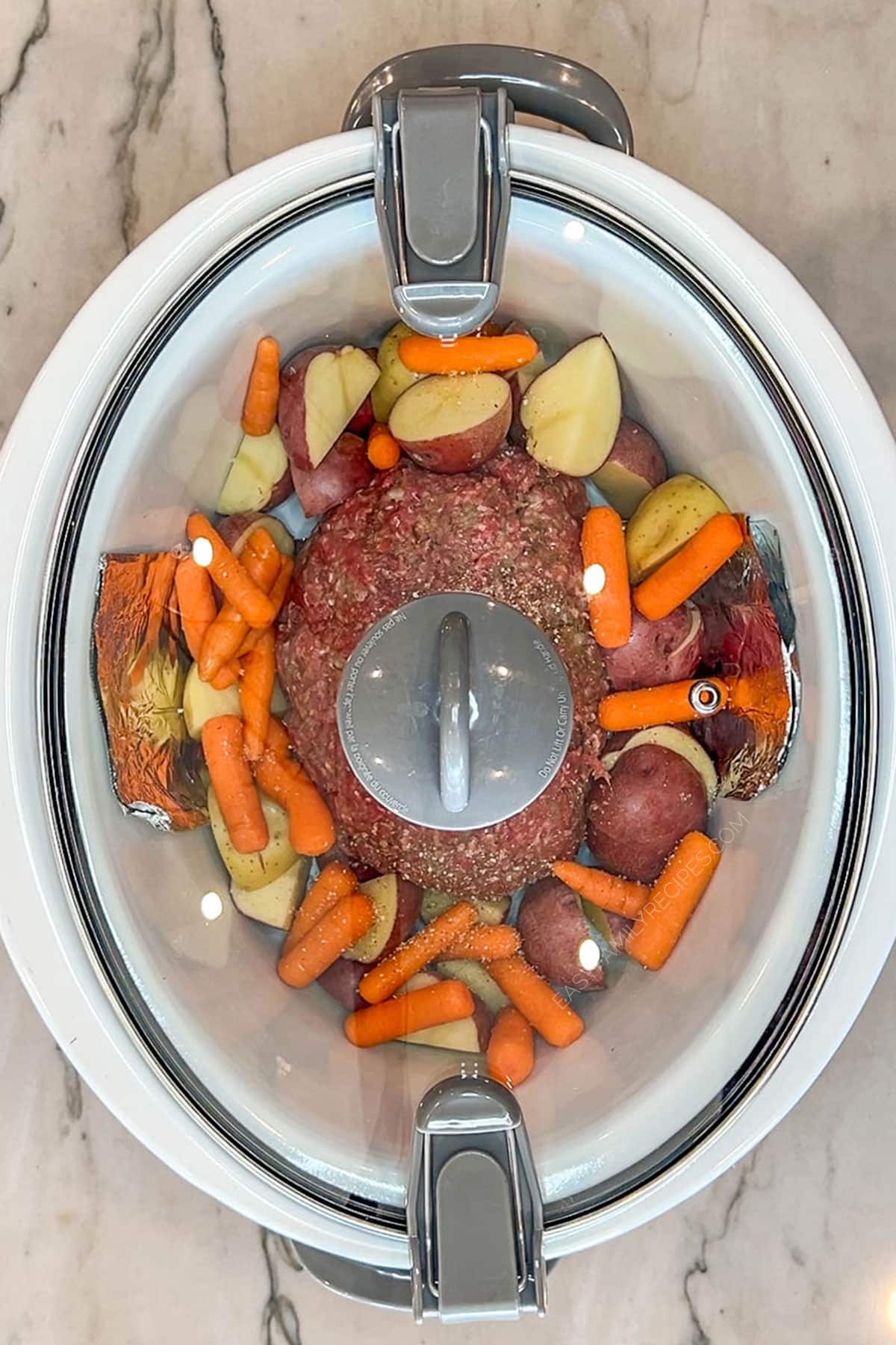 Step 2 for making Crockpot Meatloaf and Potatoes- shaped meatloaf in crockpot with carrots and potatoes around it