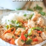 Baked chicken curry served in a bowl with rice on the side.