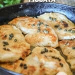 Side view of chicken picatta in a skillet.