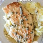 Chicken piccata served on a plate with mashed potatoes.