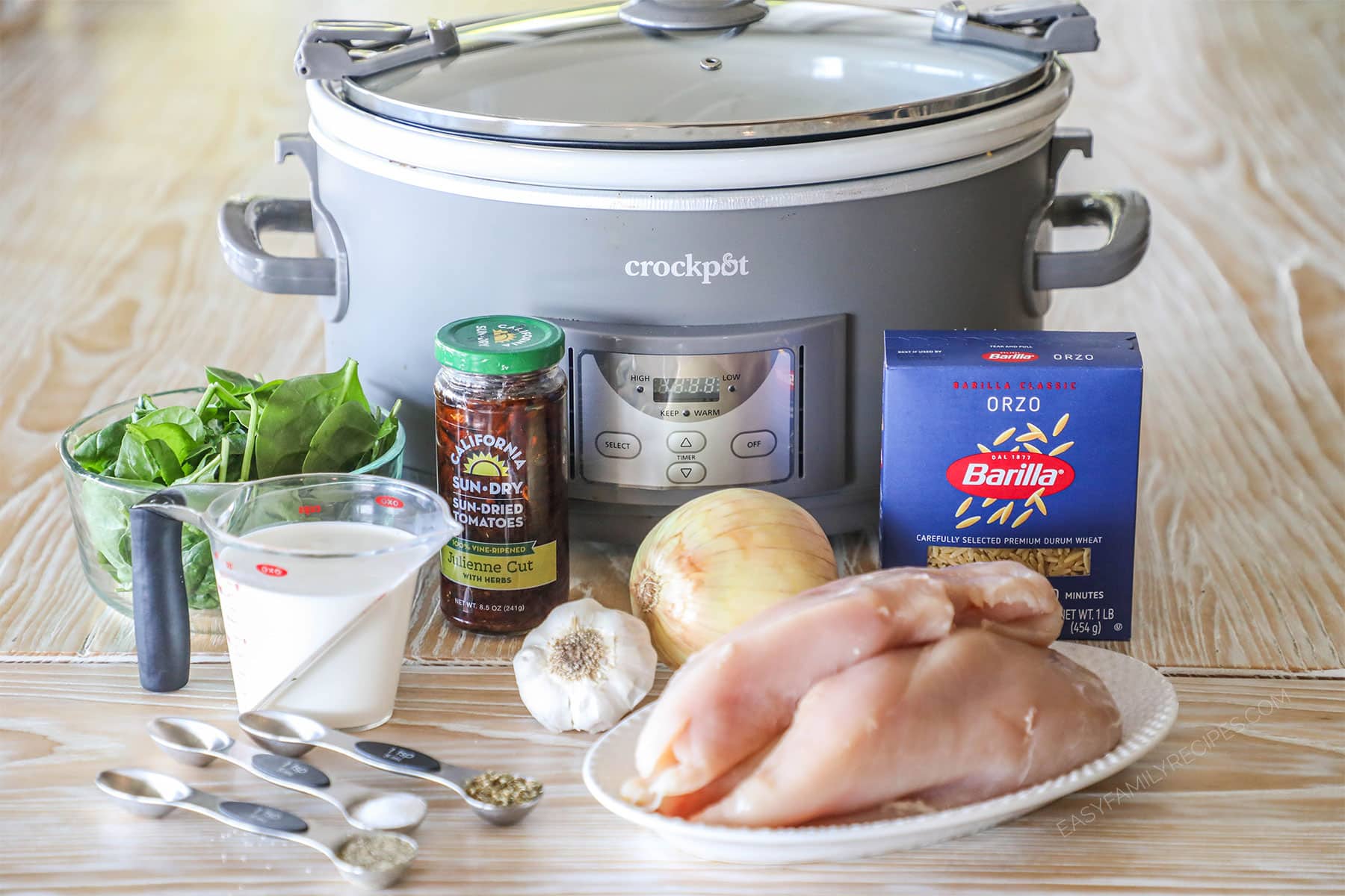 Ingredients needed to make crockpot tuscan chicken on a wooden background.
