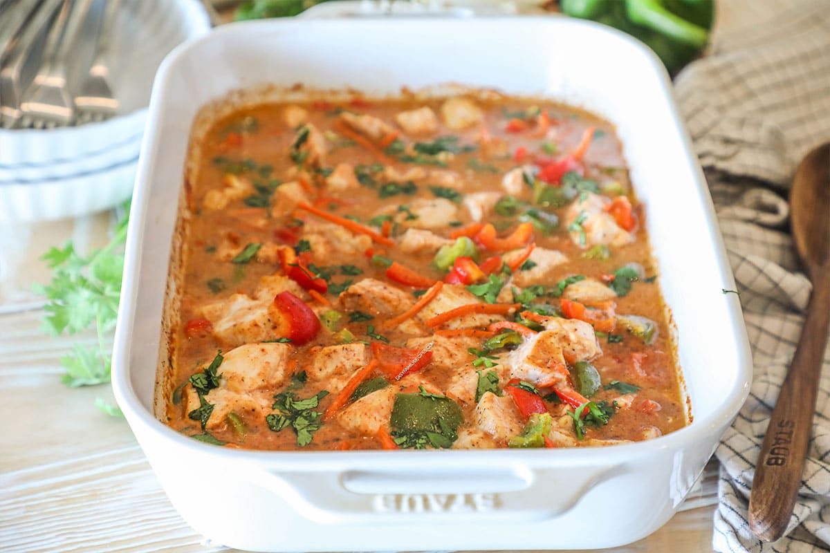 Side view of baked chicken curry in a baking dish with cilantro on top.