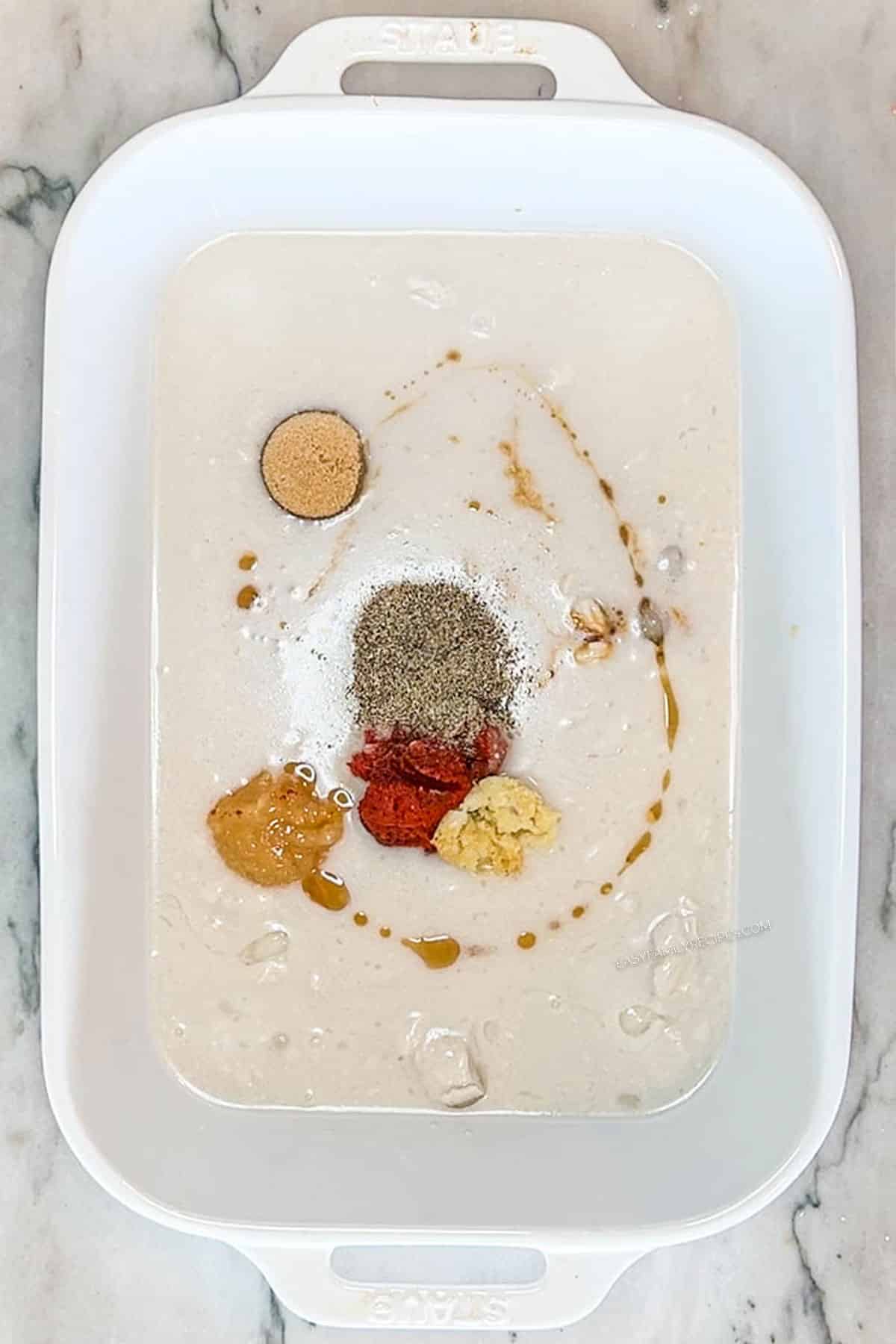 Coconut milk with spices and curry paste in a baking dish.