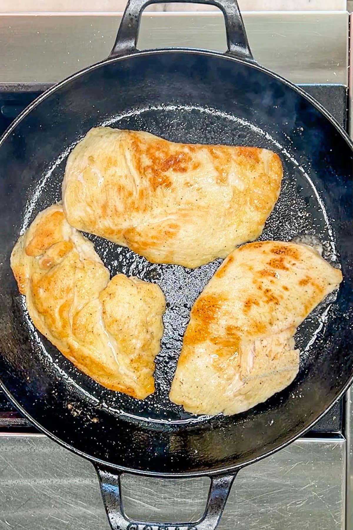 Searing chicken breast in a skillet.