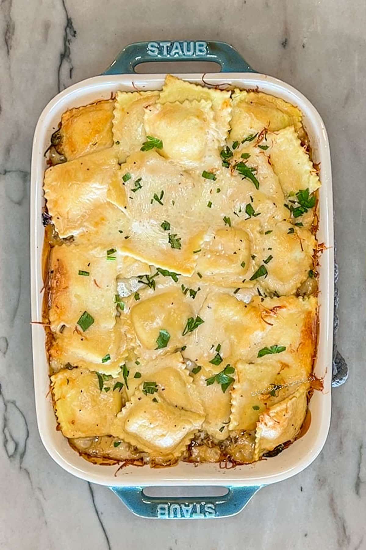 Step 6 for making Marry Me Baked Ravioli Casserole. Bake casserole. In a blue casserole dish on a marble background