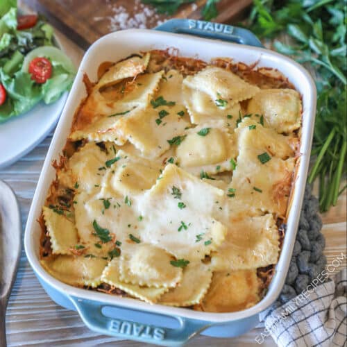 Marry Me Ravioli Casserole in blue baking dish with fresh spinach and side salad in background