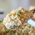 Neiman Marcus Chicken Casserole in white baking dish with wooden spoon lifting out