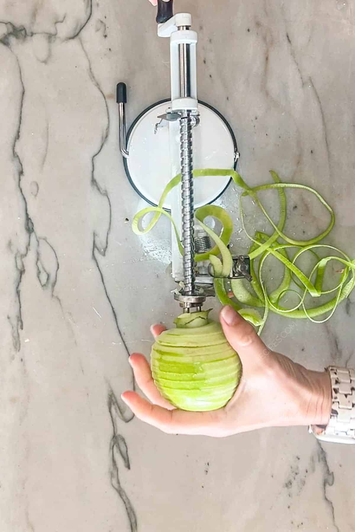 Using an apple peeler to peel a green apple.
