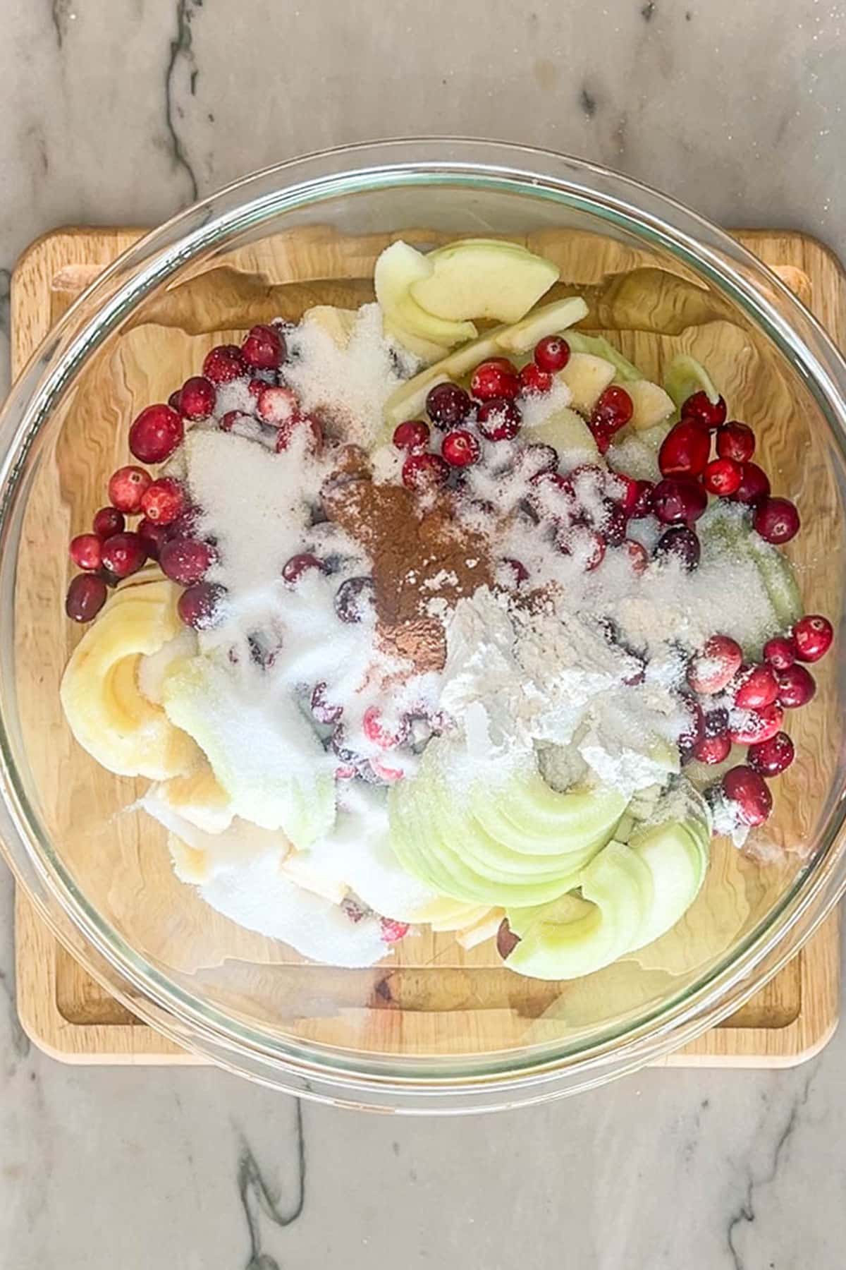 Apples, cranberries, spices, sugar and cornstarch in a bowl.
