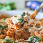 Side view of a serving spoon with baked pepperoni rigatoni on it.