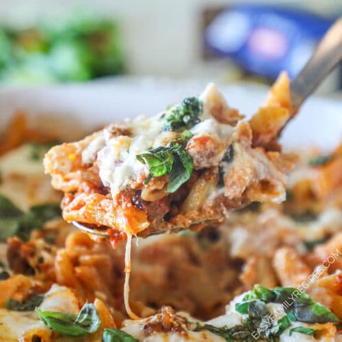 Side view of a serving spoon with baked pepperoni rigatoni on it.