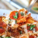 Serving spoon with baked pepperoni rigatoni on it.