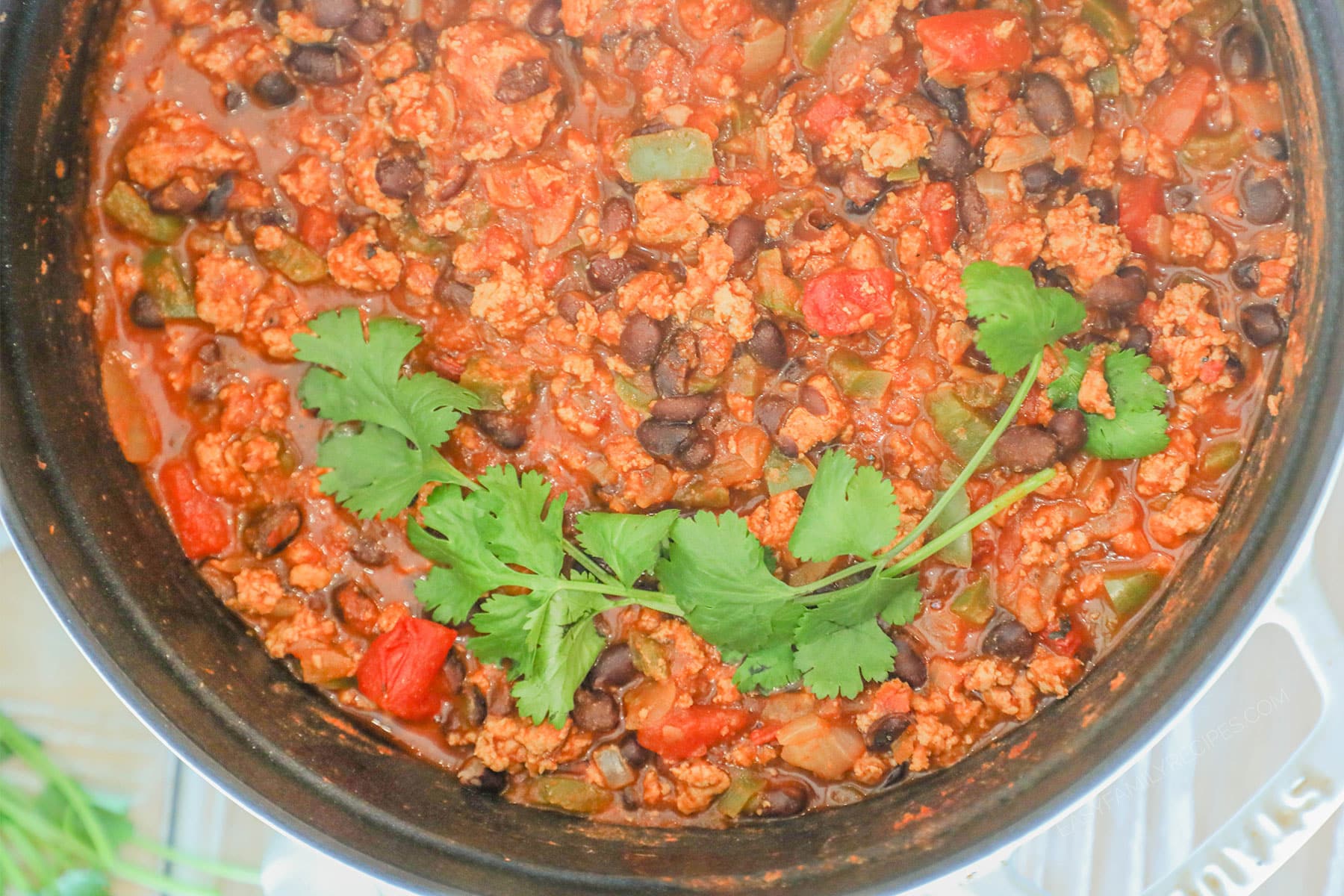 Close up of large pot of Chipotle Black Bean Ground Turkey Chili with fresh cilantro leaves on top