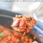 Close up of a full pot of Chipotle Black Bean Ground Turkey Chili with a spoon lifting out