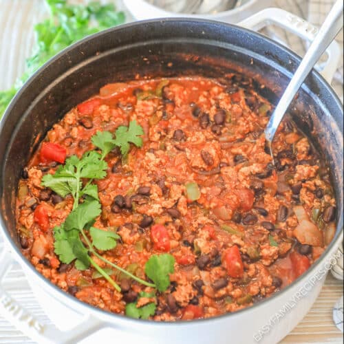 White pot of Chipotle Black Bean Ground Turkey Chili with a spoon