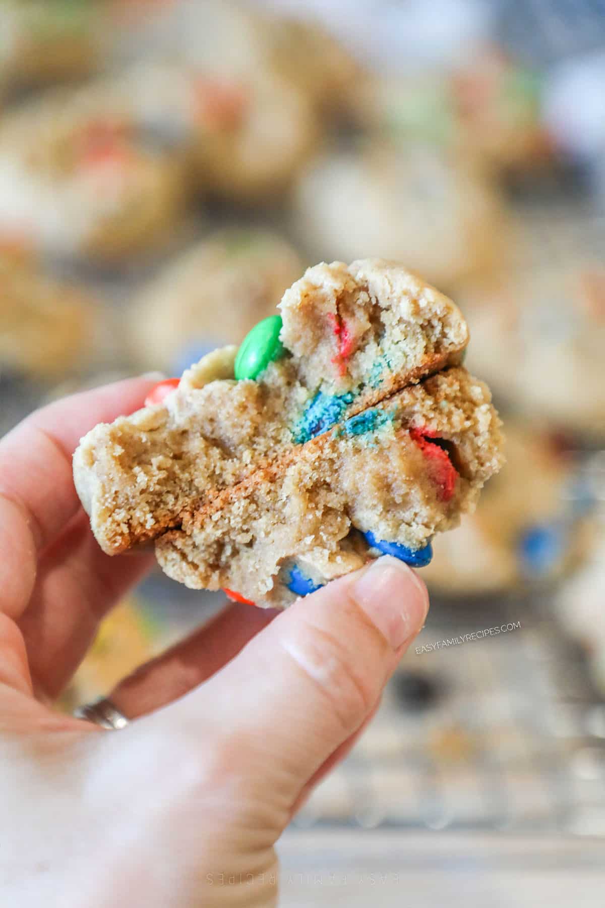 two halves of a peanut butter M&M cookie, held.
