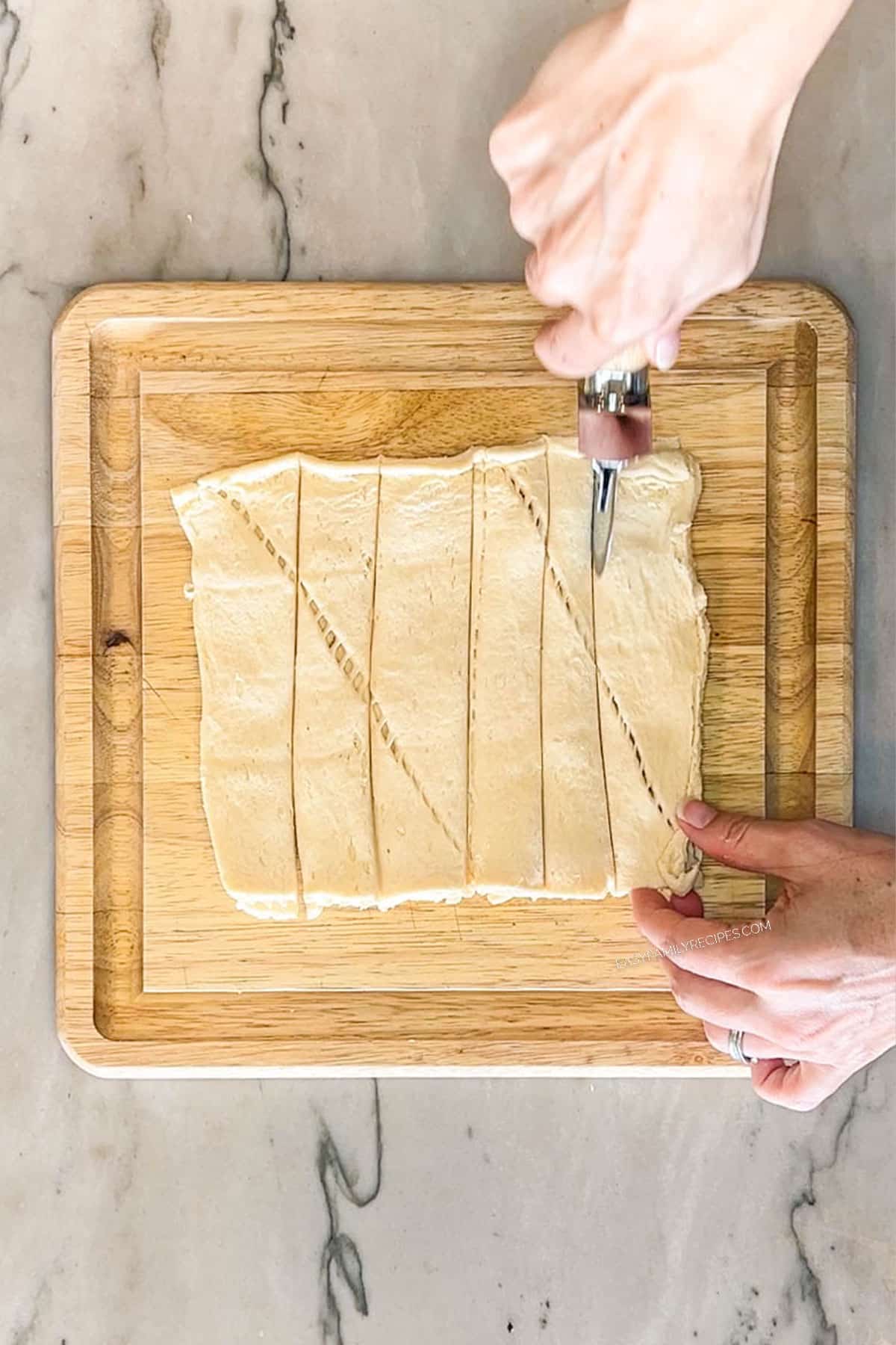 Step 2 for making Chicks in a Blanket. Slice the crescent roll sheet into 8 strips of dough.