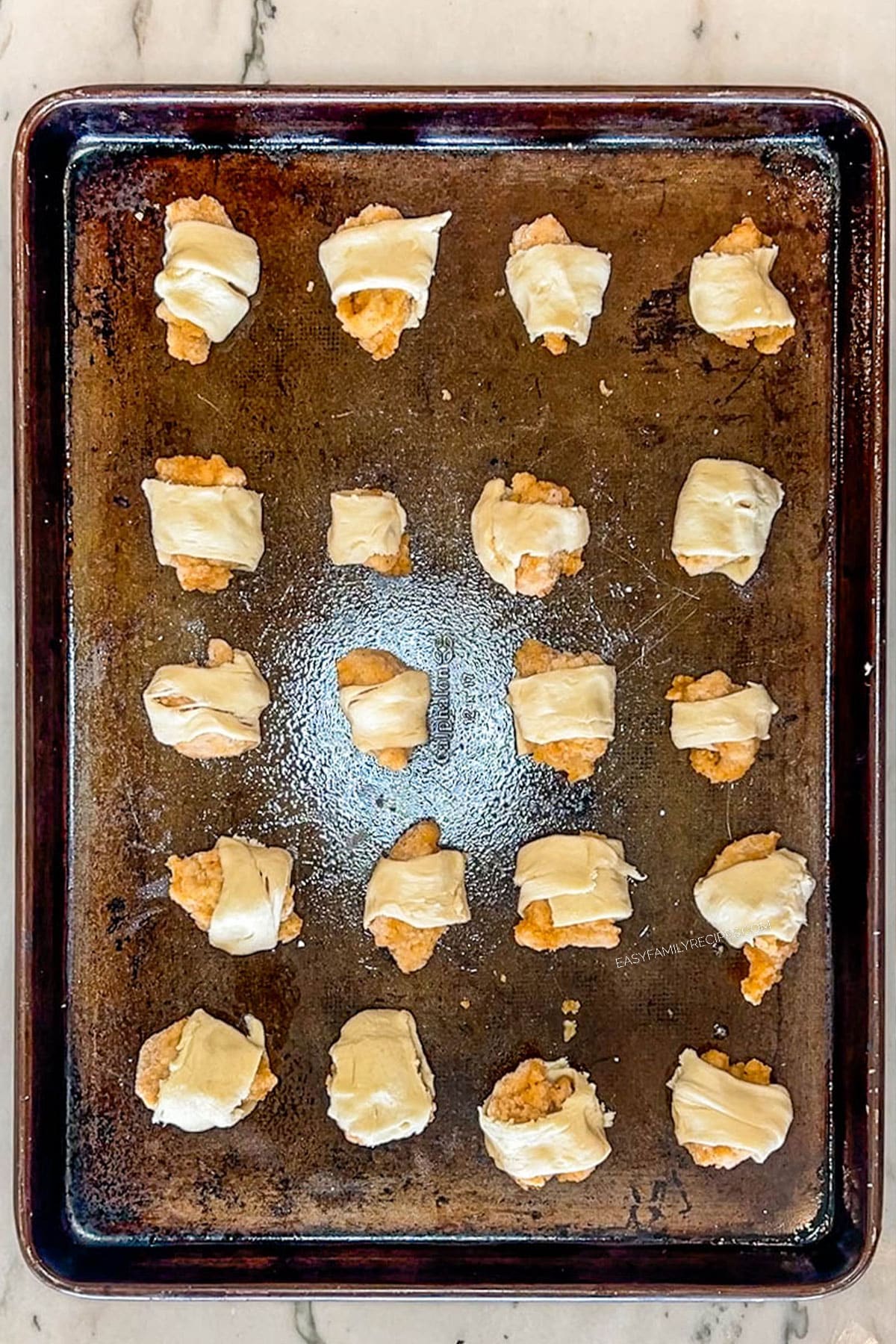 Step 4 for making Chicks in a Blanket. Wrap each nugget with crescent roll dough.