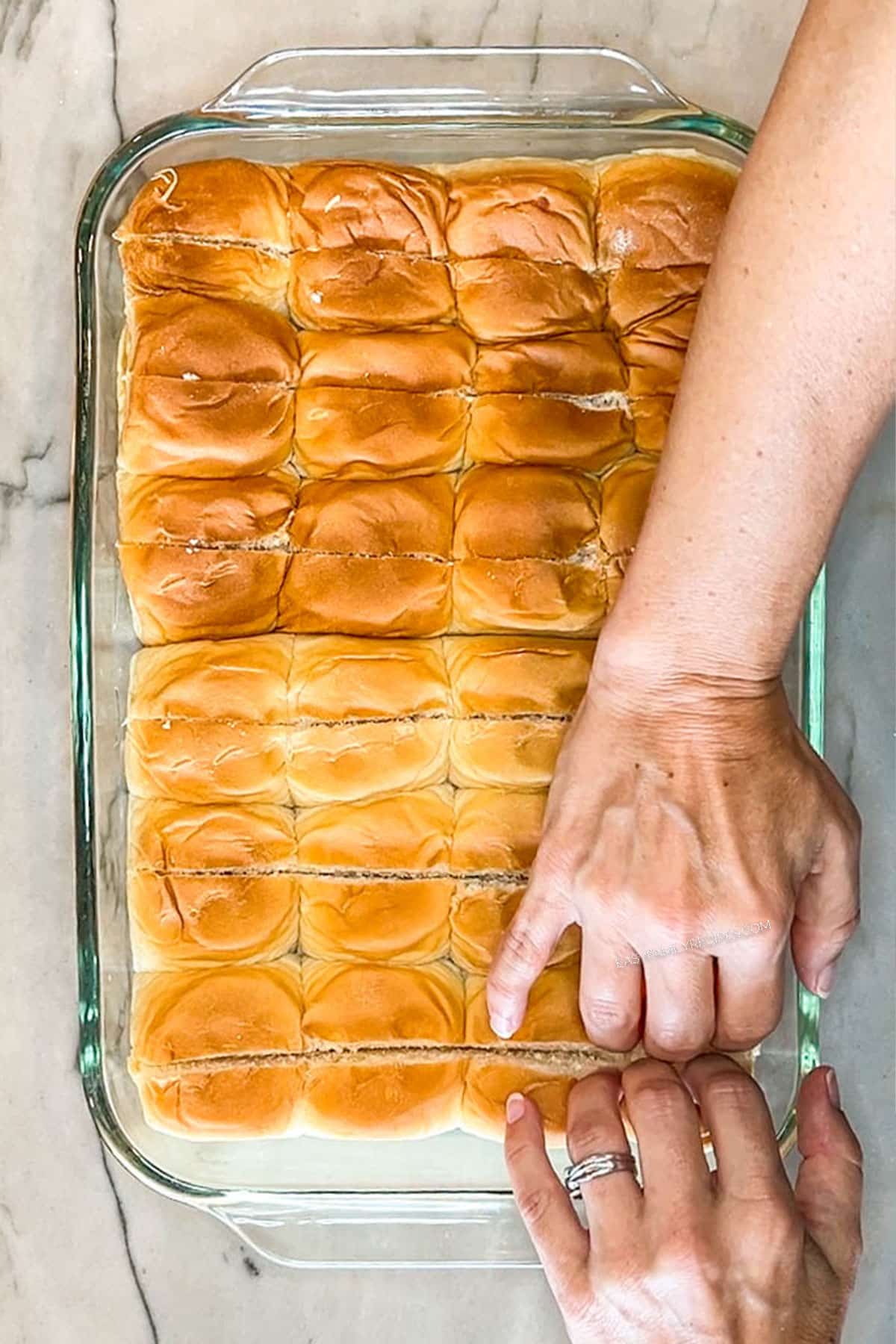 Step 1 for making Chili Dog Sliders. Place Hawaiian Rolls into 9x13 pan. Slice rolls lengthwise to make "mini buns"