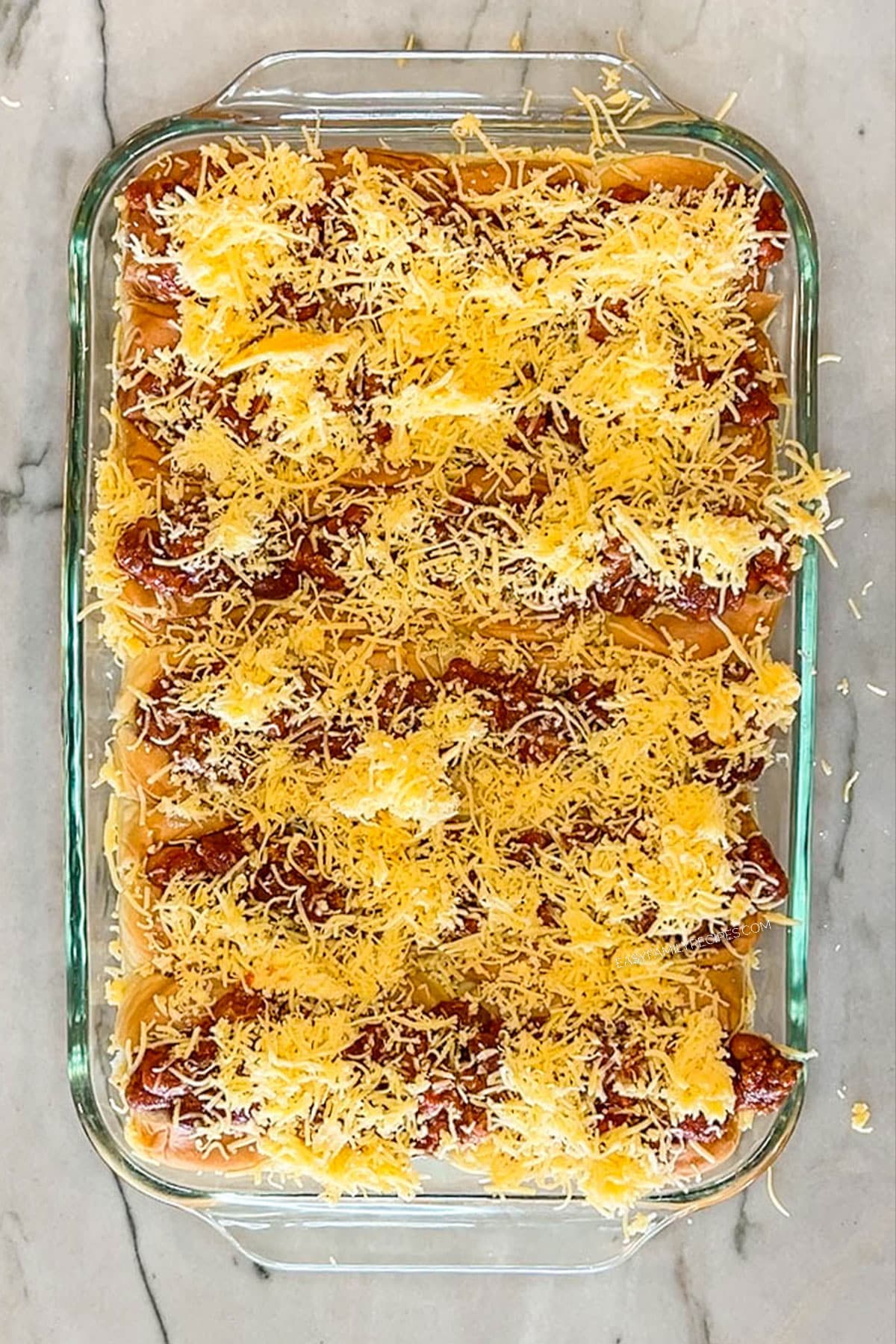Step 5 for making Chili Dog Sliders. Top with shredded cheese