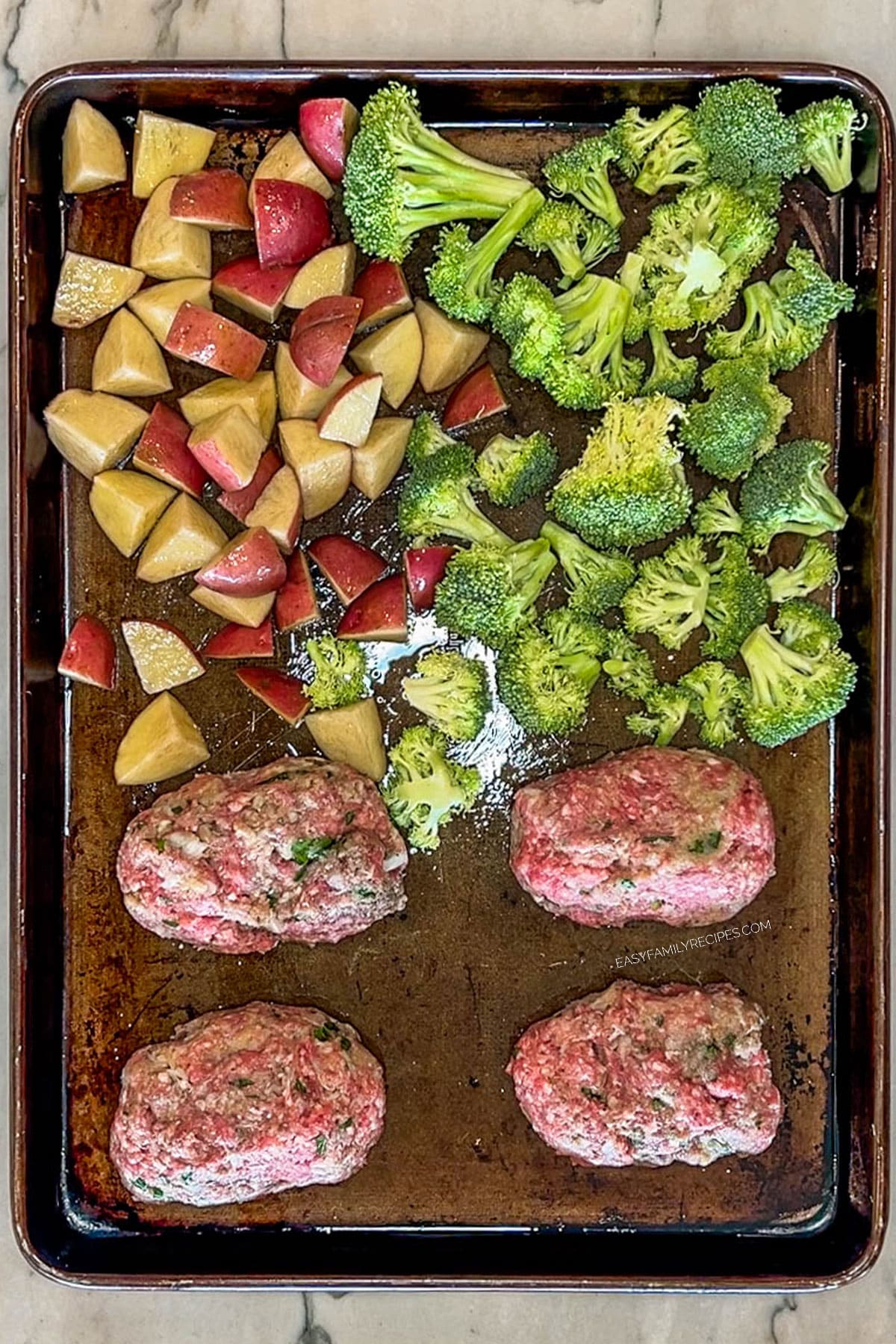 Step 3 for making Mini Meatloaf Sheet Pan Dinner. Form the meat into 4 equal meatloafs. Add potatoes and broccoli to pan