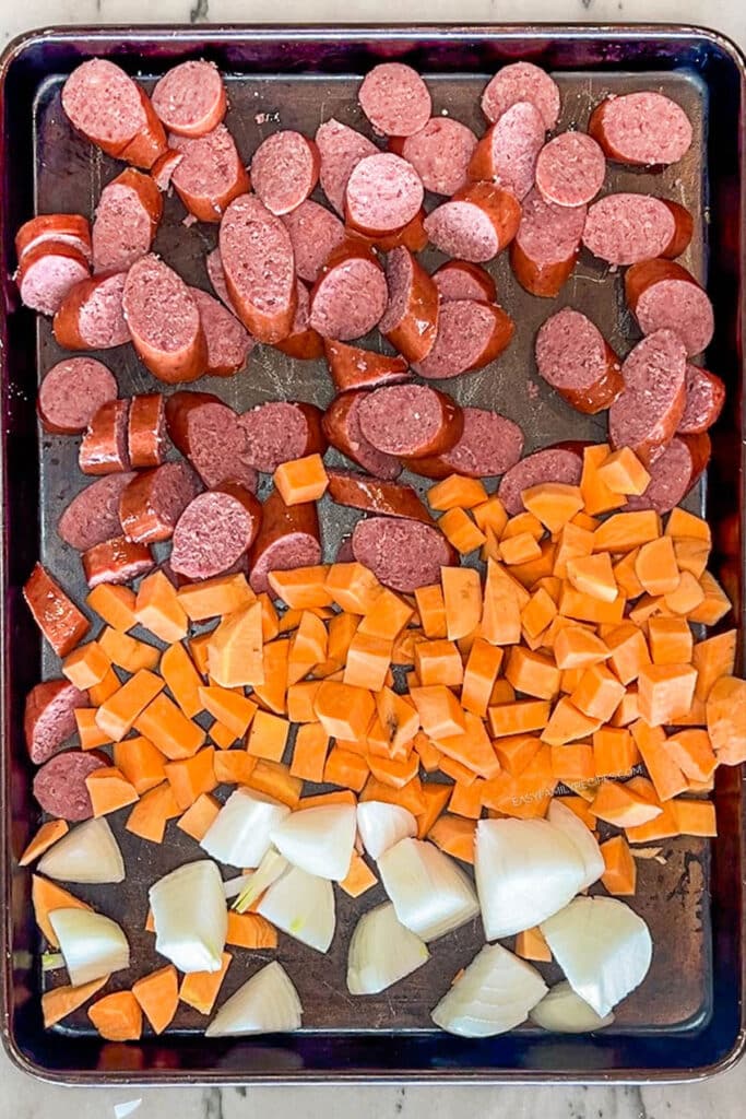 Sausage, sweet potatoes, and onions on sheet pan.