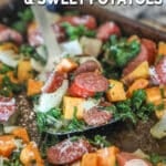 Spatula scooping sheet pan sausage and sweet potatoes from pan with text overlay that reads sheet pan sausage and sweet potatoes.