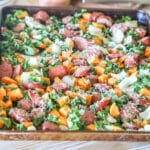 Sheet pan sausage and sweet potatoes with kale, onions, and Parmesan.