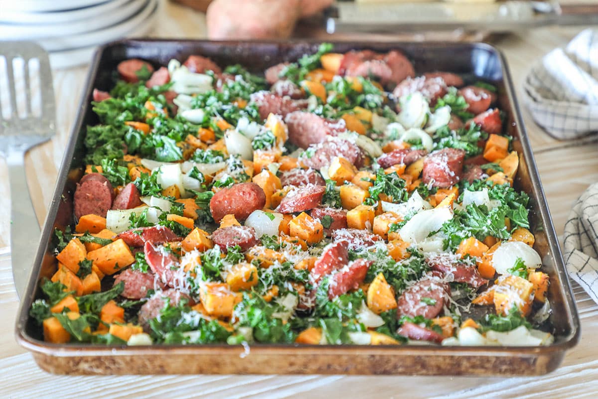 Sheet pan sausage and sweet potatoes with kale, onions, and Parmesan.